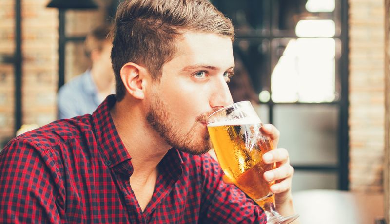 Junger Mann trinkt ein Glas Bier.