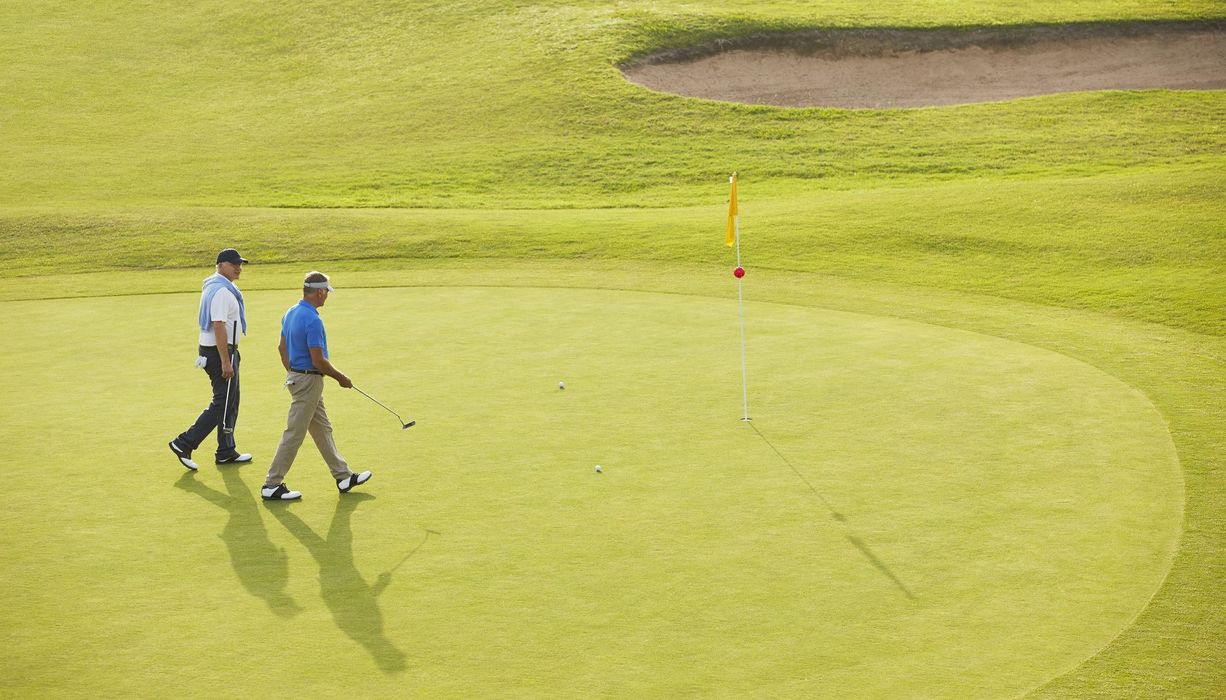 Zwei Männer, laufen über einen Golfplatz.