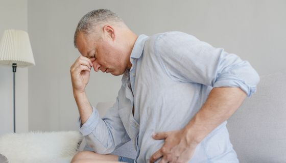 Mann in den 40ern hält sich unten links den Bauch