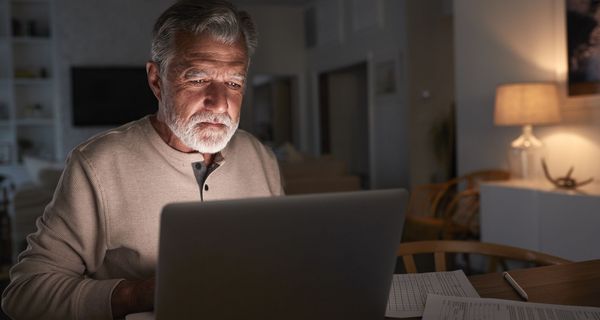 Älterer Mann, sitzt vor dem Laptop.