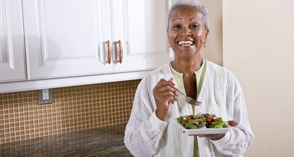 Ältere Frau, isst einen Salat.