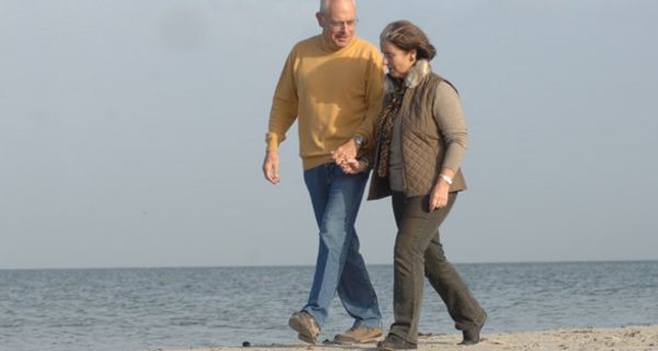 Seniorenpaar geht am Strand spazieren.