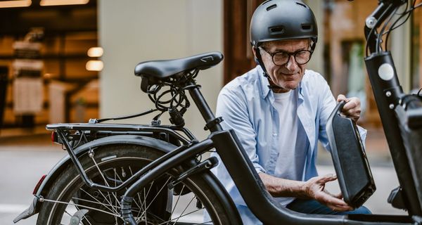 Älterer Radfahrer mit Helm, bereitet sein E-Bike vor.