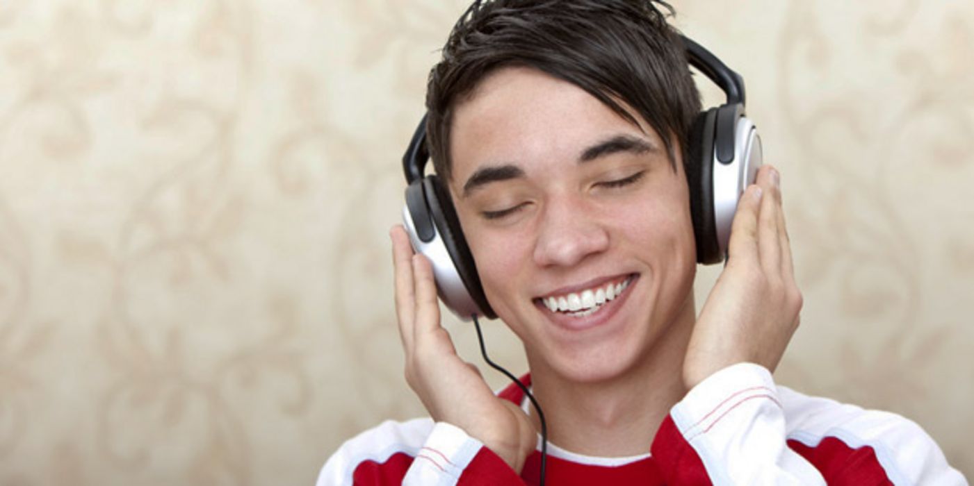 Junger Mann hört Musik mit Kopfhörern.