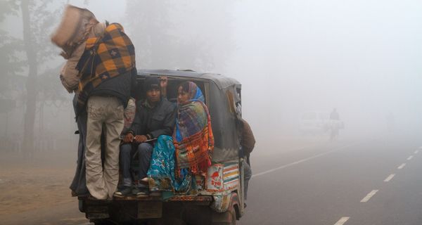 Eine indische Familie wird bei extrem rauen Wetterbedingungen in einer Auto-Rikscha transportiert. Neu-Delhi, eine landumschlossene, schnell wachsende Metropole mit mehr als 16 Millionen Einwohnern, ist in den Wintermonaten regelmäßig von Dunst und Smog (manchmal euphemistisch als Nebel bezeichnet) umhüllt, da sich Luftdruck und kühlere Luft mit Baustaub, Rauch von Kuhmistbränden und Autoabgasen vermischen, die dann tagelang über der Stadt schweben.