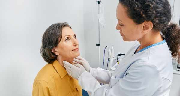 Ärztin, untersucht die Schilddrüse einer älteren Frau. 