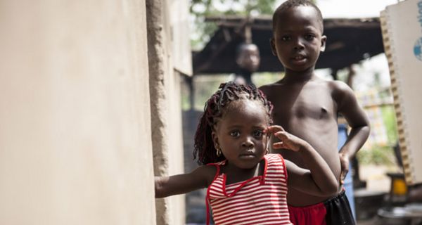 Togolesisches Mädchen im Vordergrund im rotweiß-gestreiften Kleid, ca. 3 Jahre alt, Junge im Hintergrund, nackter Oberkörper, ca. 6 Jahre alt