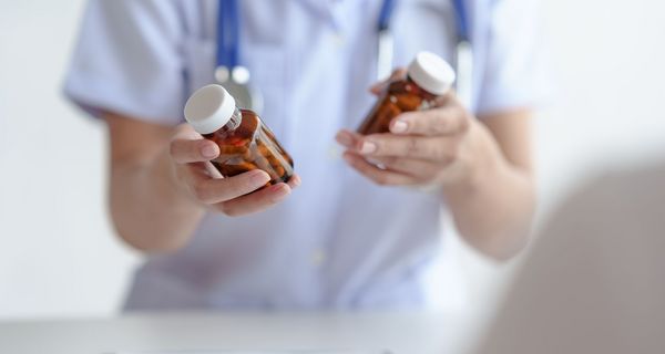 Ärztin mit zwei verschiedenen Tablettendosen in der Hand.