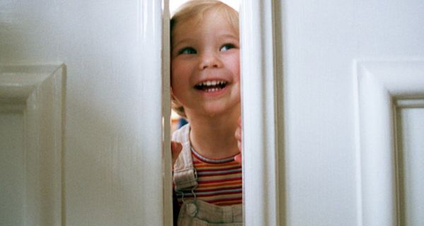 Kleines Mädchen lugt durch einen Türspalt