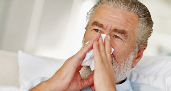 Älterer Mann schnäuzt sich die Nase