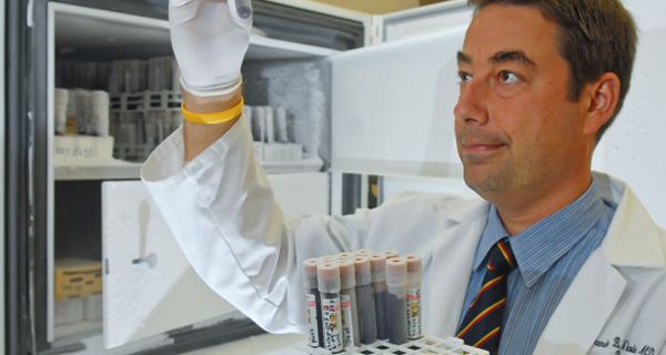 Labormitarbeiter begutachtet ein Röhrchen mit Blutprobe