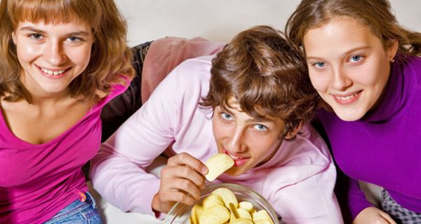 Jugendliche essen Chips auf einer Couch
