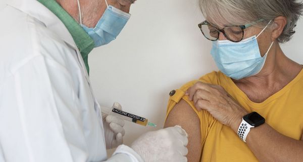 Ältere Frau wird von einem Arzt geimpft.