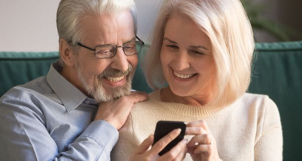 Älteres Paar schaut auf ein Smartphone.