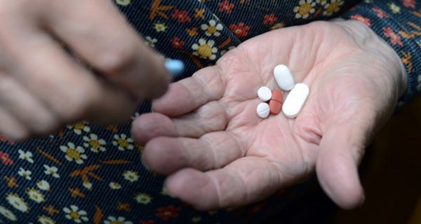 Seniorin hält mehrere Tabletten in der offenen Hand