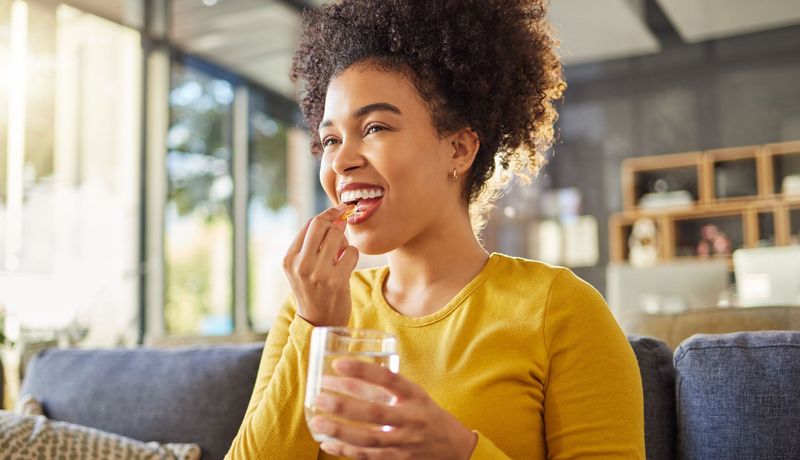 Junge Frau nimmt eine Kapsel ein.