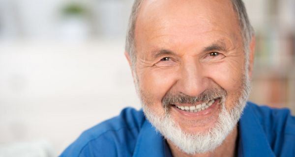 Portraitfoto weißbärtiger, vitaler Mann im blauen Hemd lächelt in die Kamera
