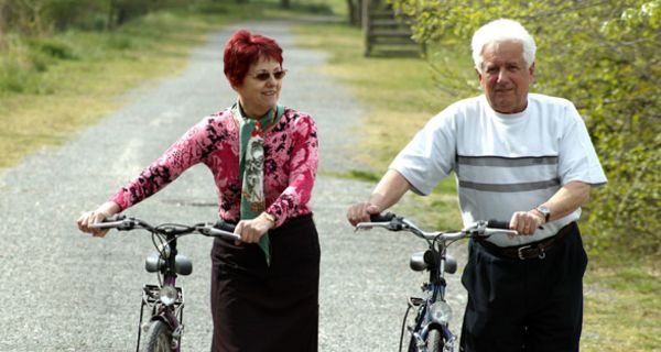 Älteres Paar schiebt Fahrräder.