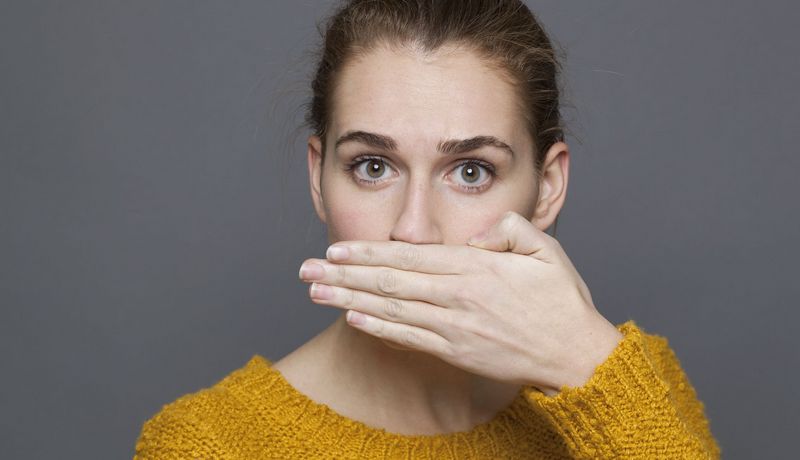 Frau hält sich eine Hand vor den Mund.