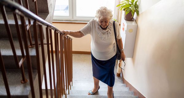 Ältere Frau, geht eine Treppe hoch.