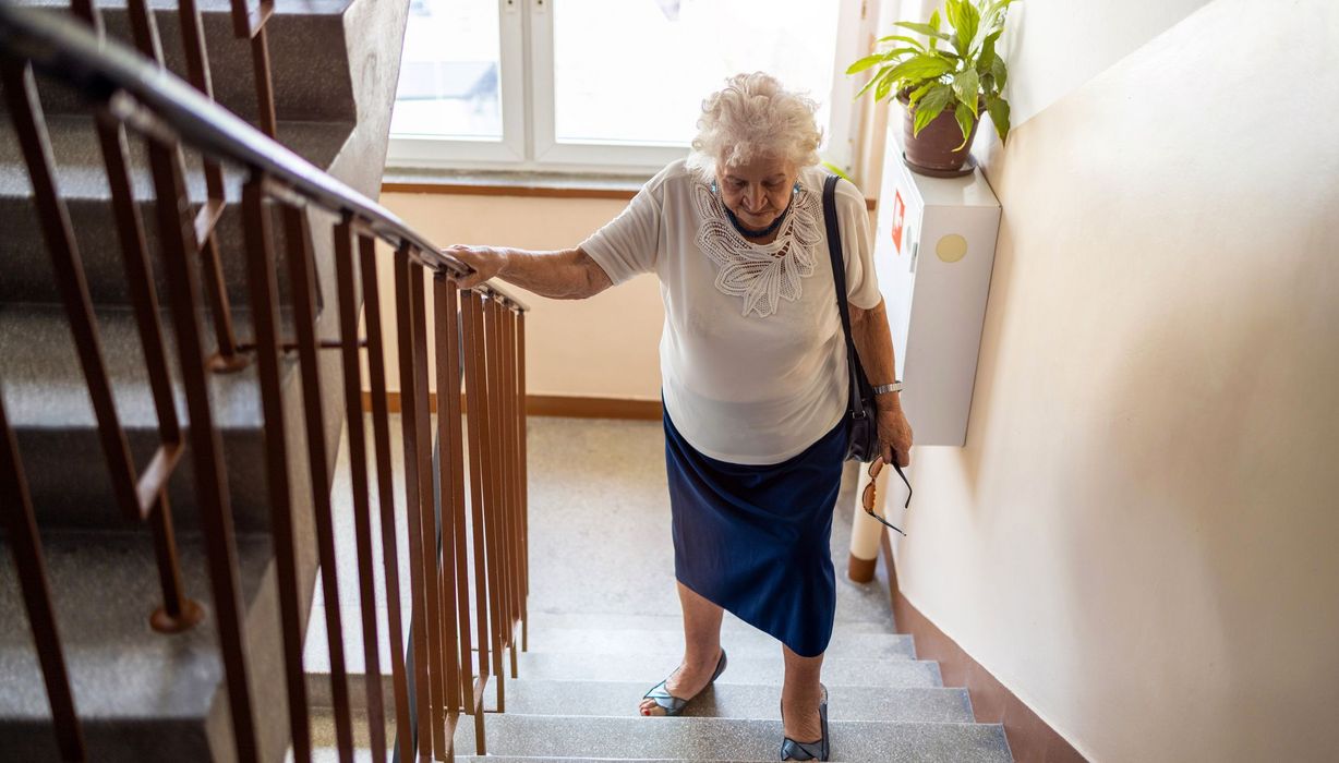 Ältere Frau, geht eine Treppe hoch.