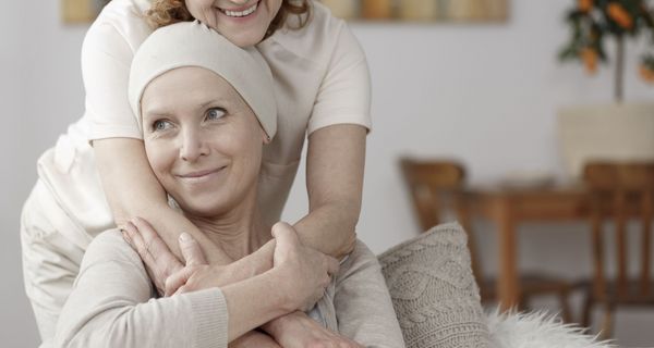 Krebspatientin wird von Pflegerin umarmt 