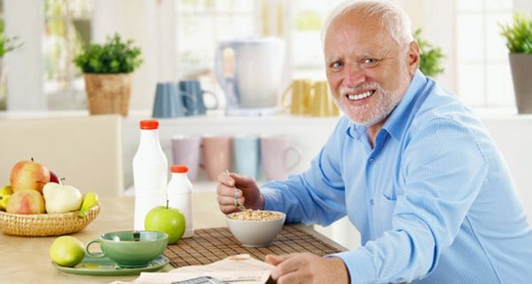 Mann sitzt an einem Esstisch und frühstückt gesund