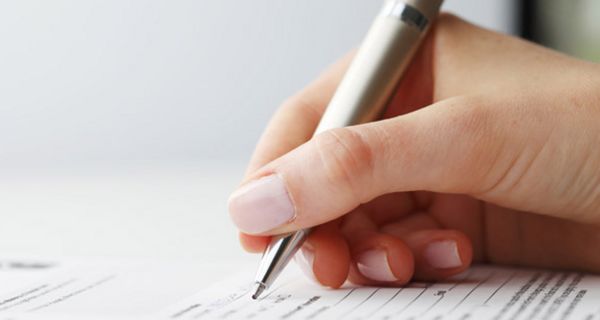 Frauenhand mit Kugelschreiber beim Ausfüllen eines Formulars