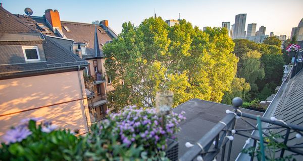 Foto von einem Balkon mit Blick in die Stadt und auf einen Baum.