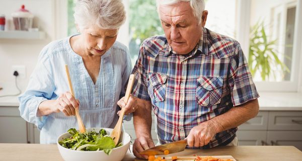 Älteres Paar bereitet Salat.