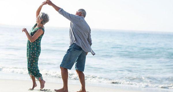 Zwei ältere Senioren, tanzen am Strand.