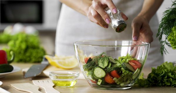 Frau salzt ihren Salat.