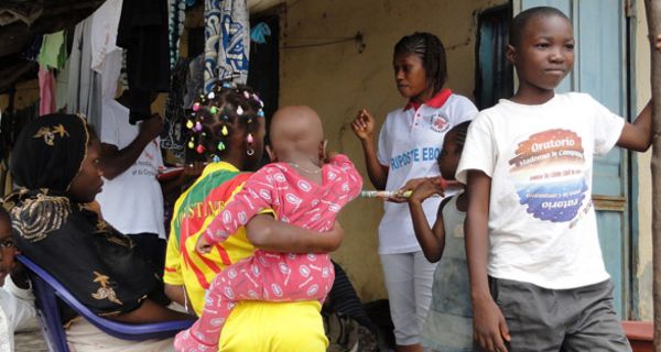 Mitarbeiterin des Roten Kreuzes in Guinea spricht mit Frauen und Kindern.