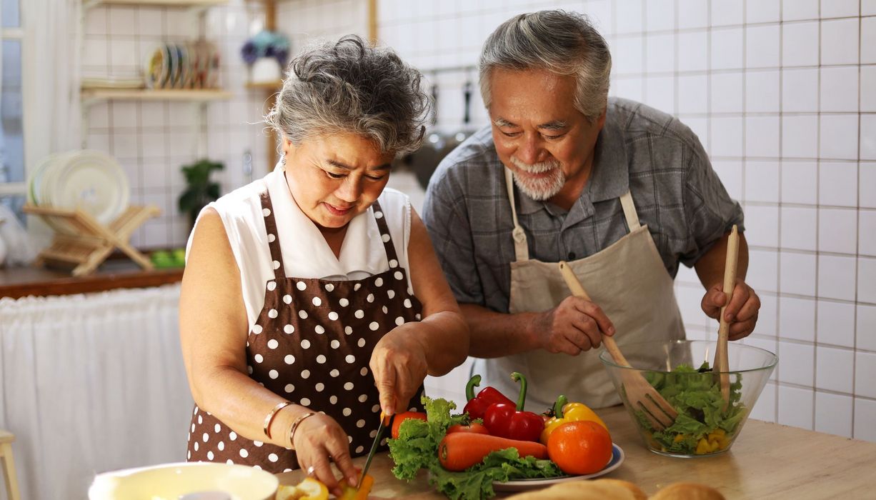 Ein älteres Paar, macht zusammen in der Küche Salat. 
