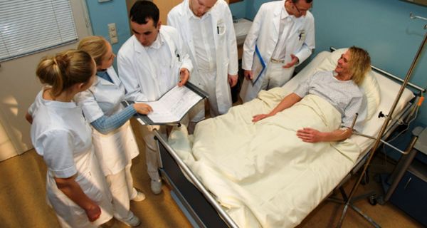 Gefahr durch Erreger: Ärzte in Arbeitskleidung stehen um ein Krankenbett.