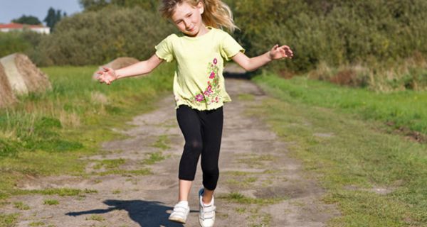 Kleines Mädchen hüpft einen Feldweg entlang