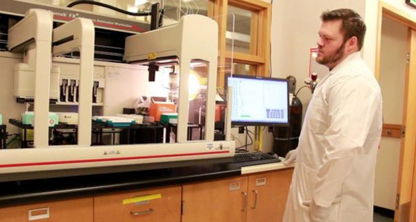 Wissenschaftler (rotbrauner Vollbart, braune Haare) im Labor vor Bildschirm