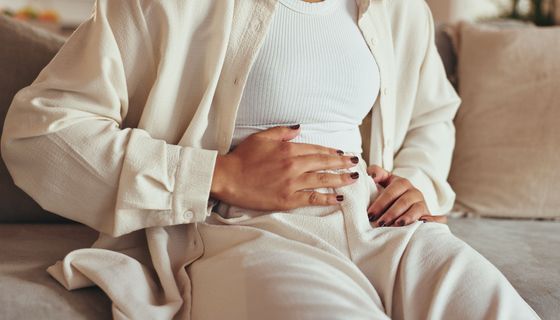 Frau, hält sich den Bauch.