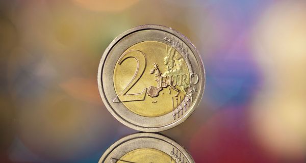 Zwei Euro Münze auf buntem, verschwommenem Hintergrund.