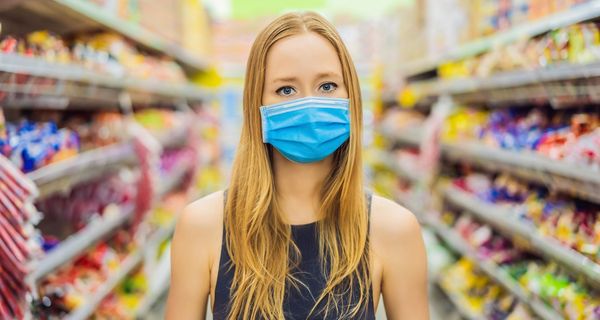Junge Frau mit Maske im Supermarkt