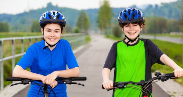 Zwei lächelnde Mädchen mit Fahrradhelmen.