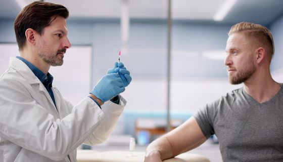 Ein Arzt bereitet eine Spritze für einen Patienten vor.