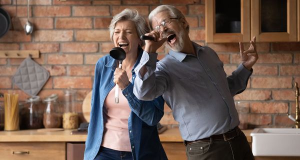 Zwei ältere Senioren, singen zusammen in der Küche.