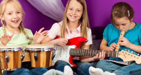Drei Mädchen spielen Instrumente: Trommel, Gitarre, Flöte
