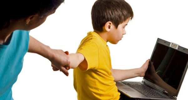 Mutter zieht Jungen vom Computer weg.