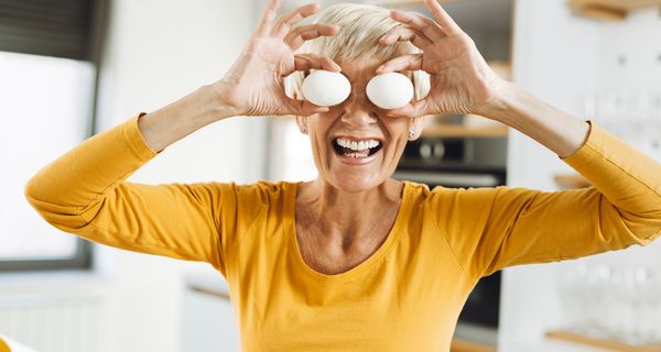 Ältere Frau, lacht und verdeckt ihre Augen mit zwei Eiern.