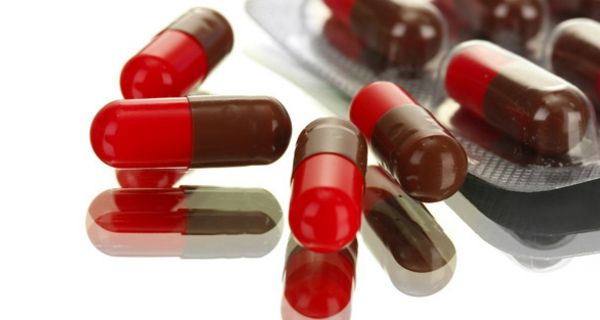 Arzneimittel-Blister mit rot-grünen Kapseln auf einem Tisch mit Glasplatte