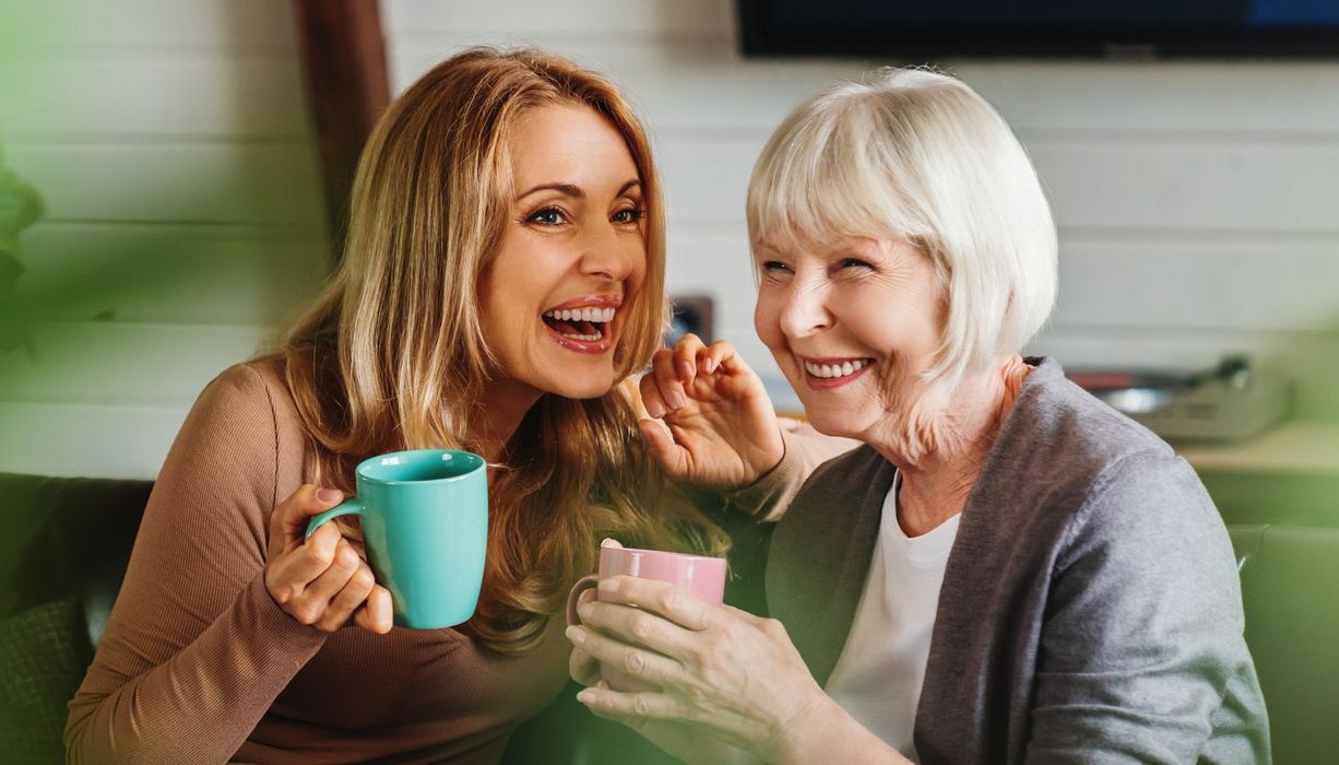 Zwei glückliche Frauen sitzen zusammen und trinken eine Tasse Tee