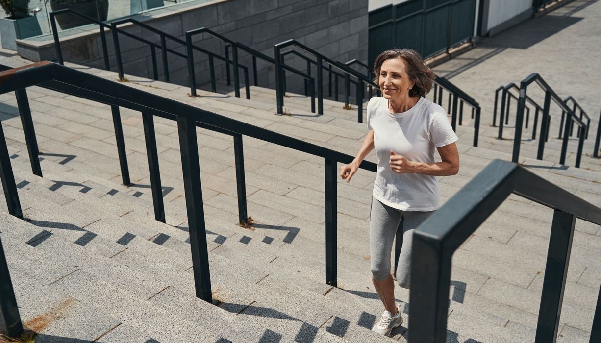 Frau, joggt eine Treppe hoch.