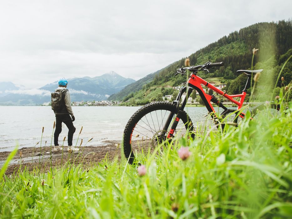 Mann, steht am Fluss, im Vordergrund sein Fahrrad.